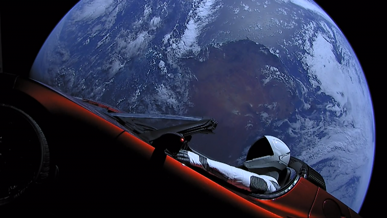 Photograph of a Tesla being driven by a SpaceX spacesuit above planet earth